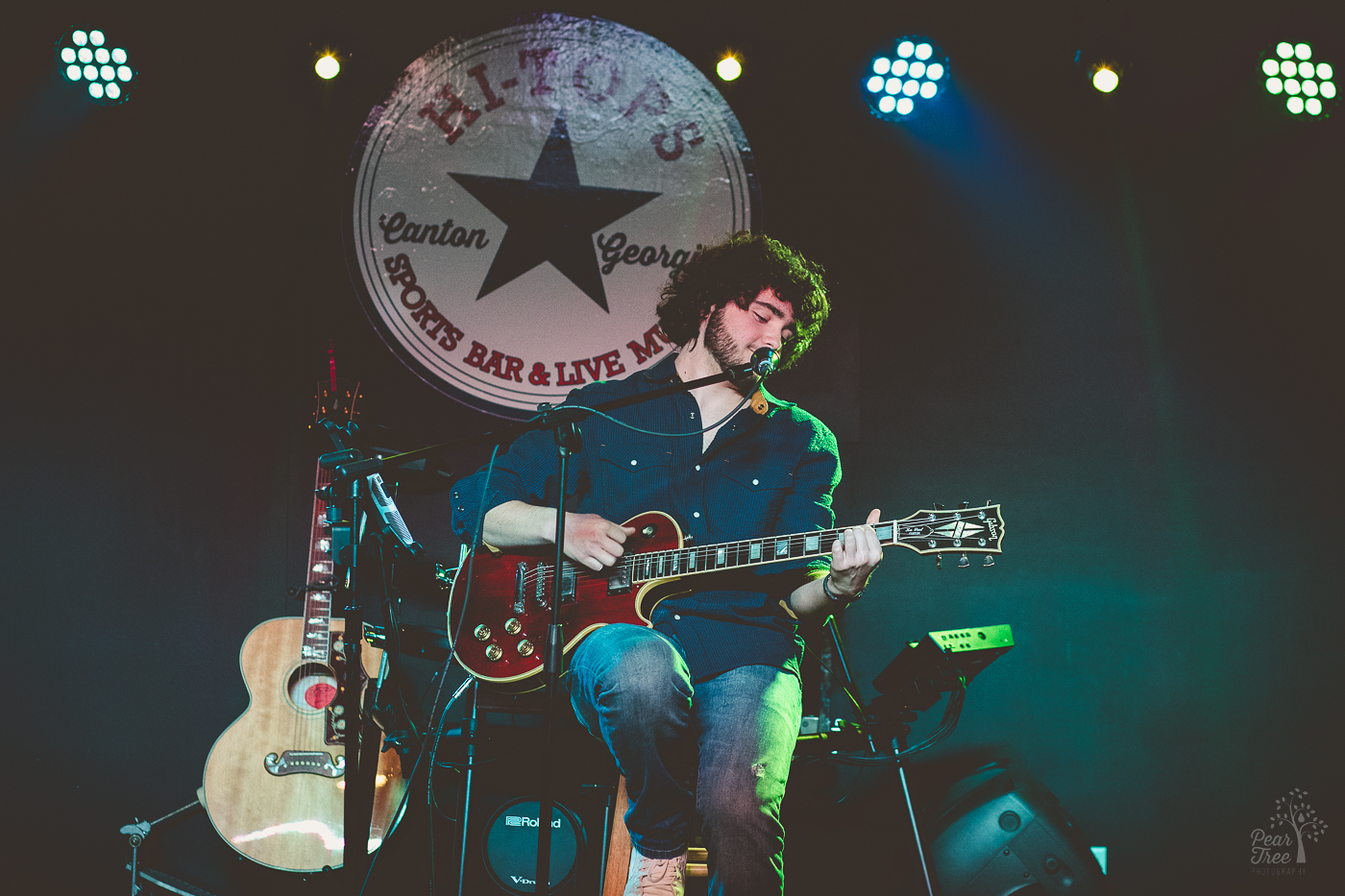 High school boy performing on stage at HI-TOPS SPORTS BAR playing his guitar and singing