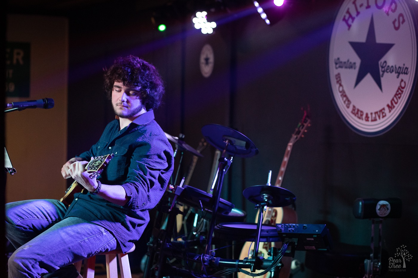 Hunter Rose leaning back on his stool on the HI-TOPS SPORTS BAR LIVE MUSIC stage and playing his guitar