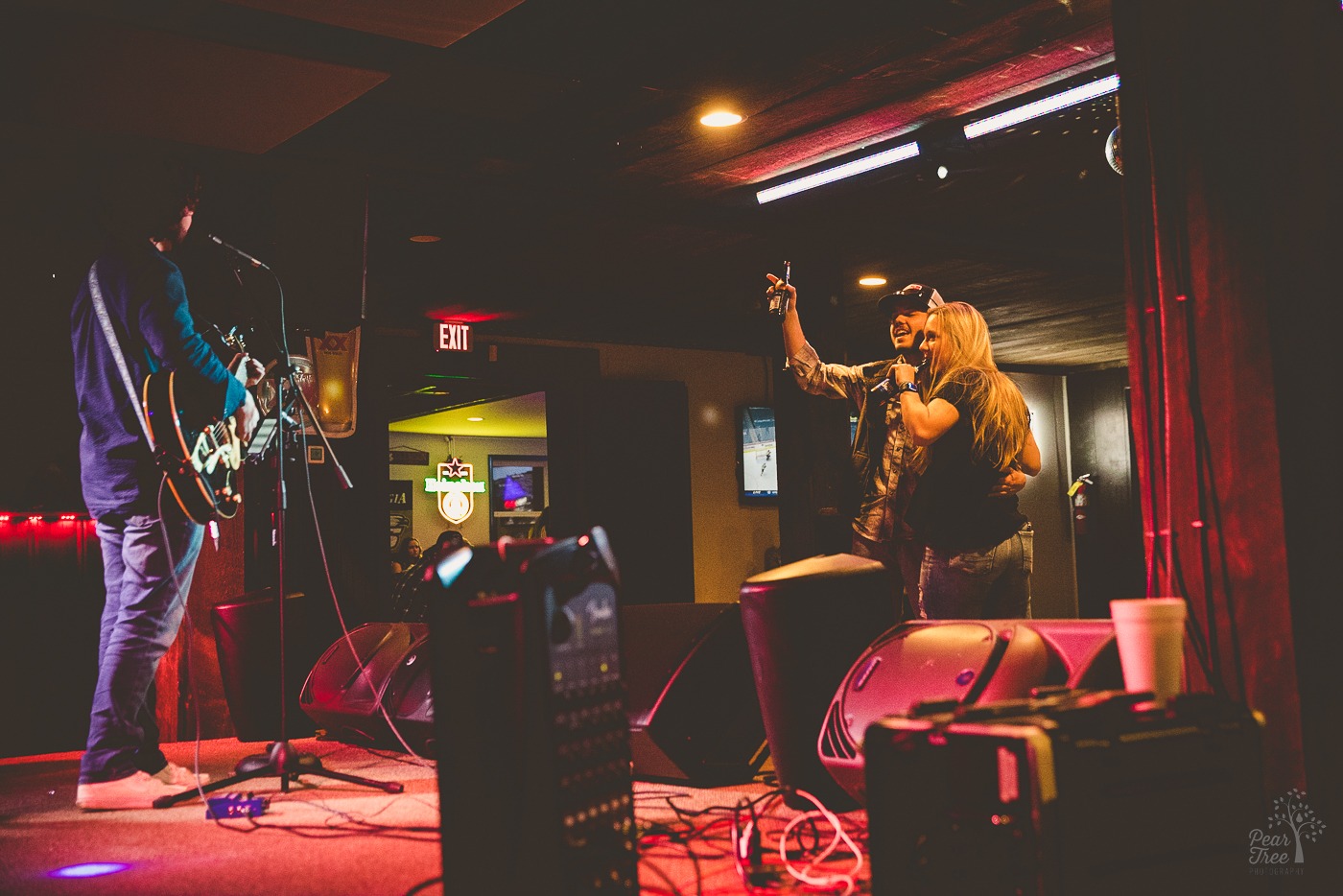 A couple dancing and drinking beers in HI-TOPS SPORTS BAR are raising a beer to the live acoustic singer performing onstage