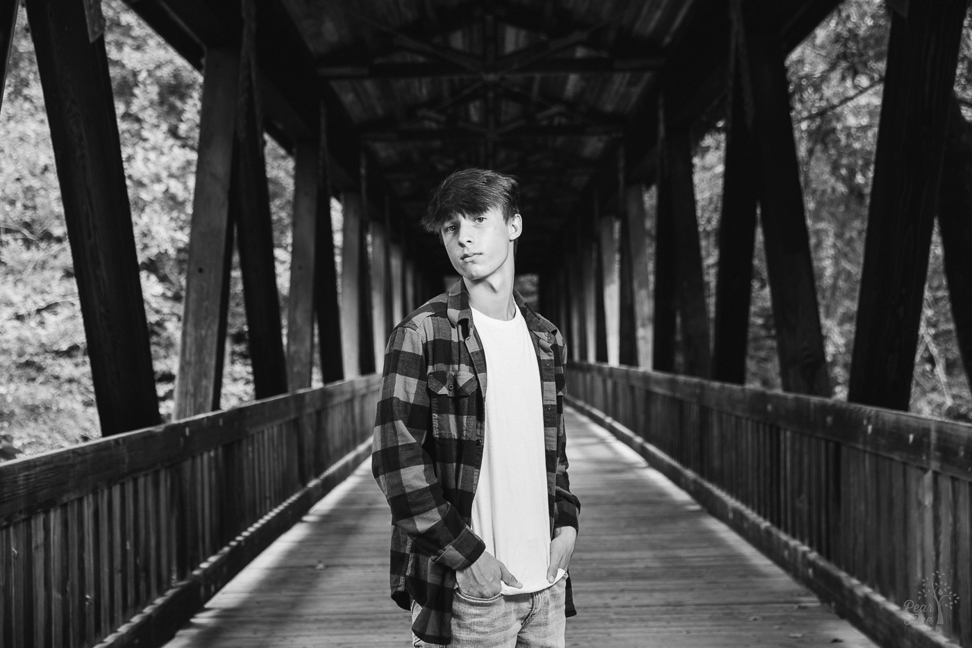 Black and white photo of a teenage boy standing on Roswell Mill covered bridge