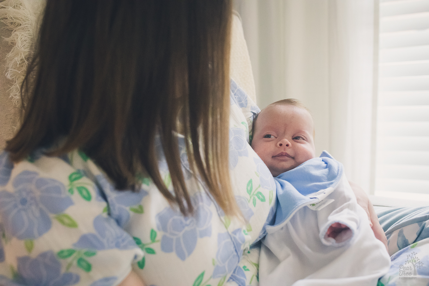 Mom is holding newborn son close while he smiles and looks content