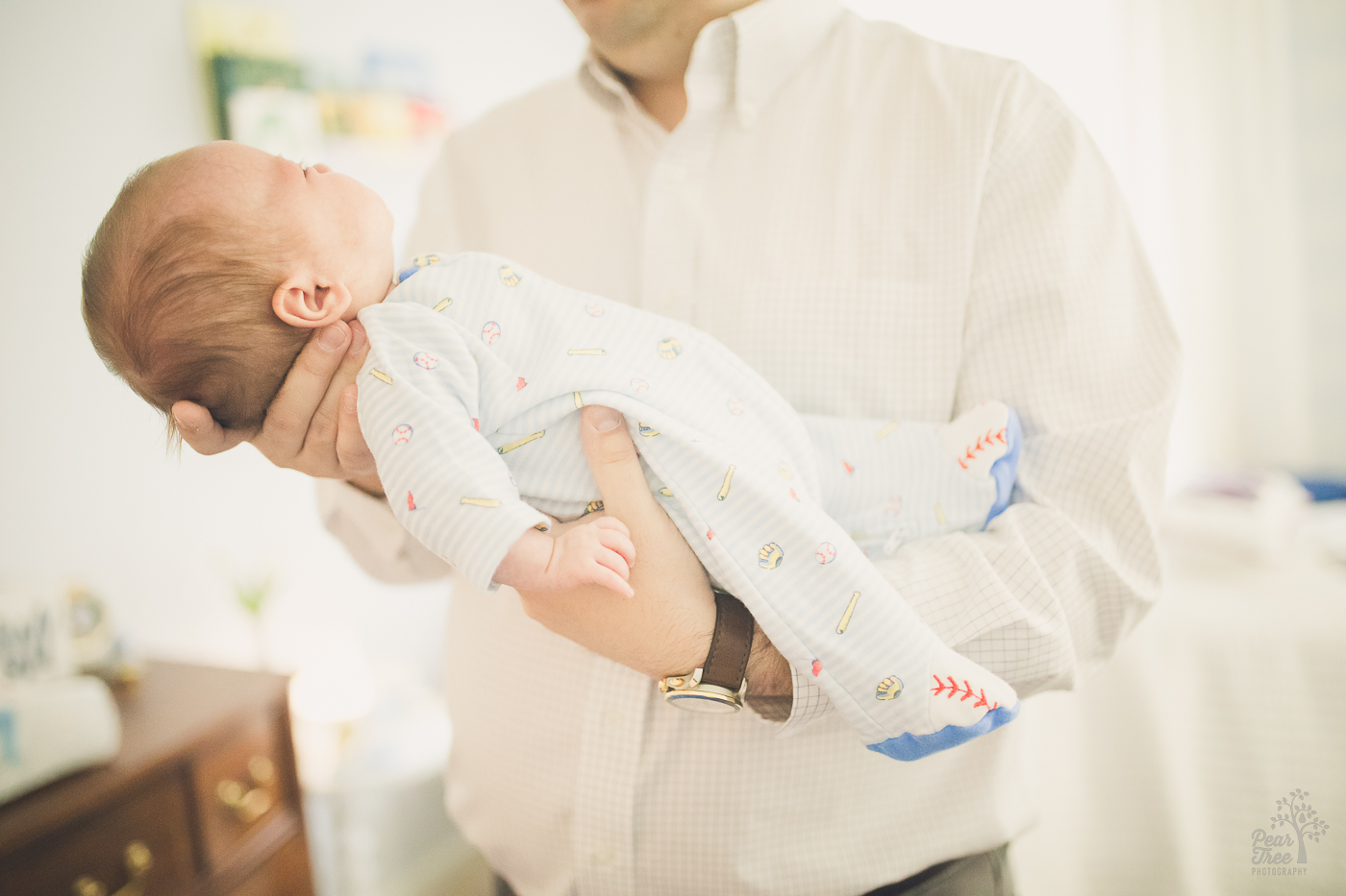 Dad holding his baby boy wearing a baseball onesie