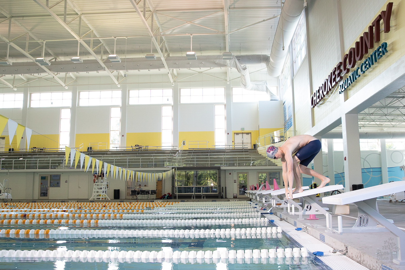 Woodstock high school senior boy swimmer preparing to jump off the Cherokee County Aquatic Center diving block into the indoor pool