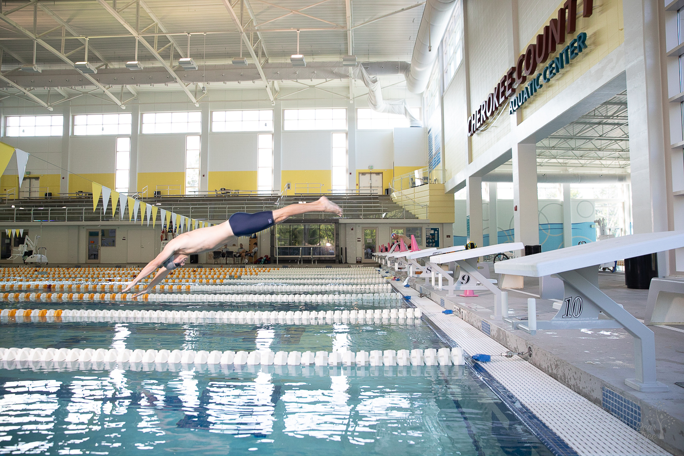 High school senior boy diving into the indoor Cherokee Aquatic Center pool