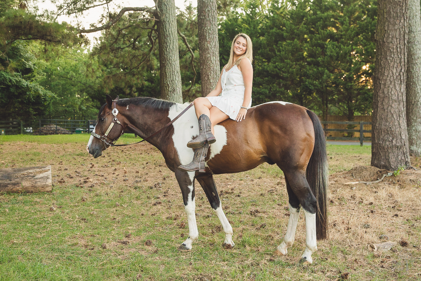 Senior photographs with a horse while the girl sits with legs crossed on his back
