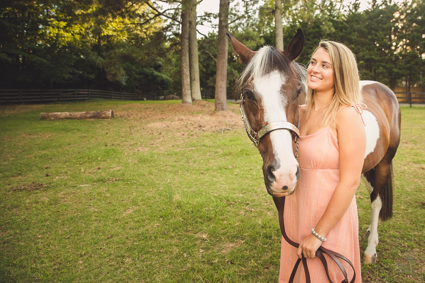 A high school senior girl smiling while getting irritated over her horse pushing his ears back