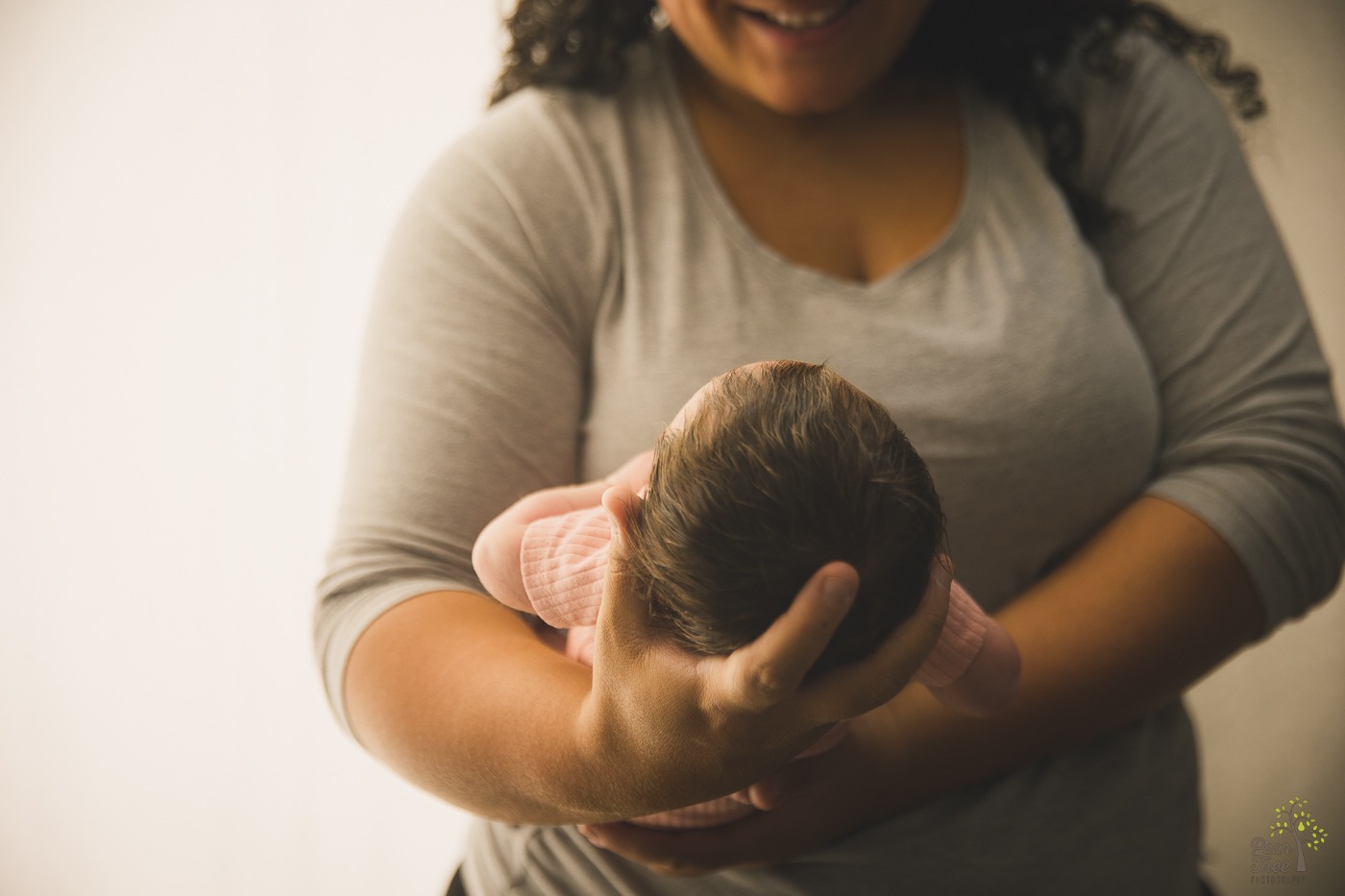 Mom smiling while holding newborn daughter in front of her chest