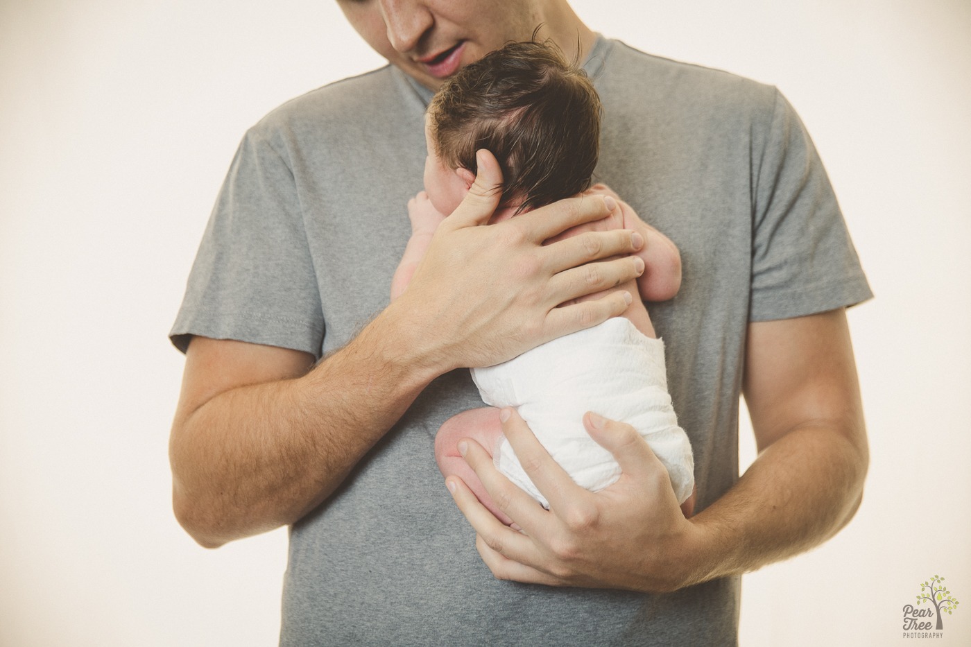 Dad smiling and holding newborn daughter close to his chest