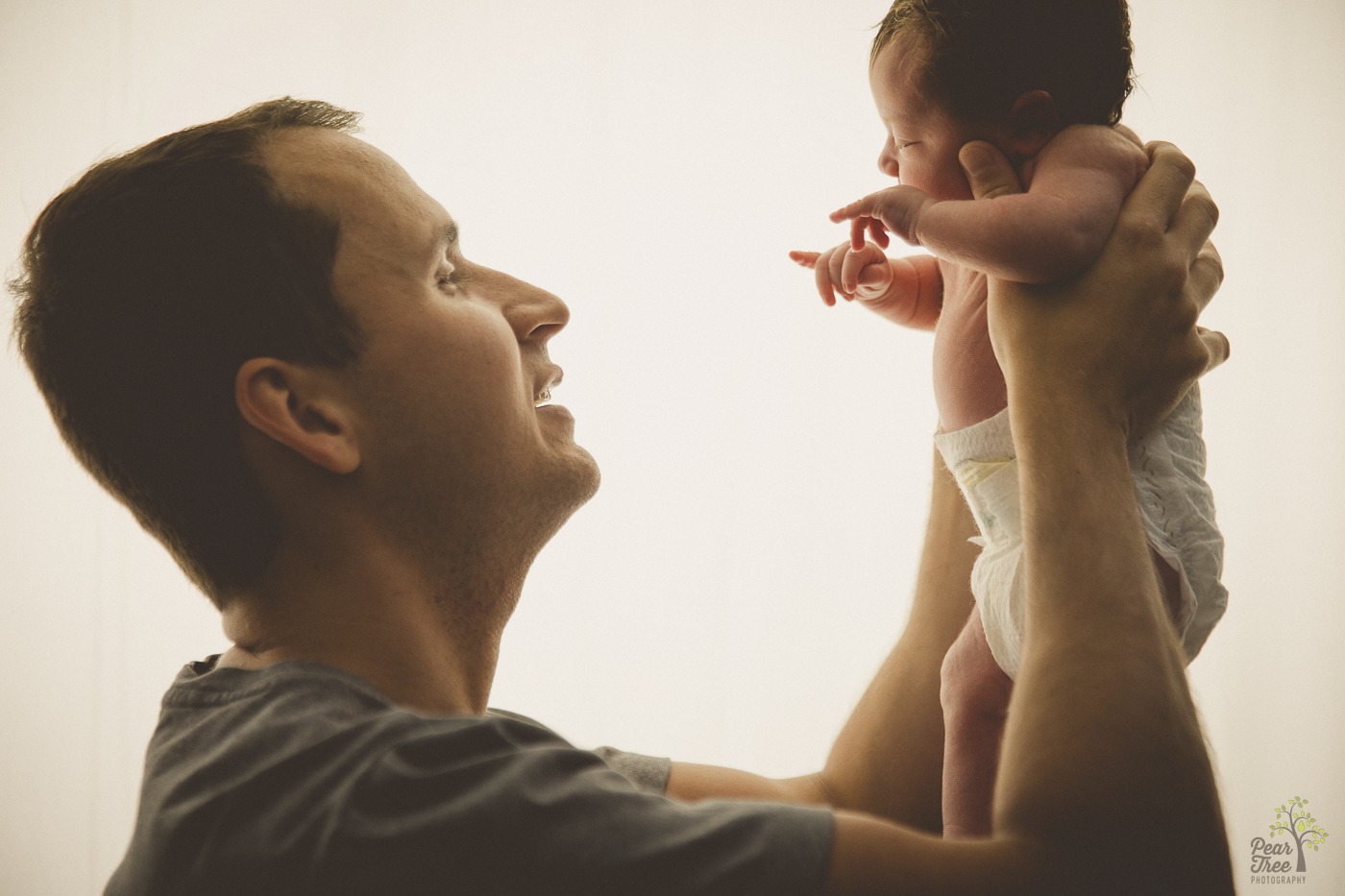 Father smiling and holding his newborn daughter up above his shoulders