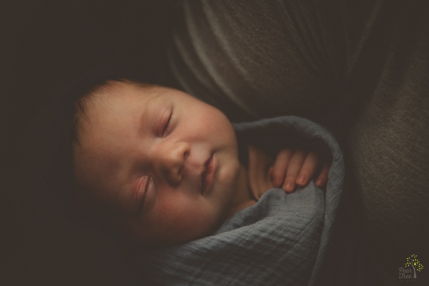 Newborn baby girl wrapped in a blanket and held close to mom's chest