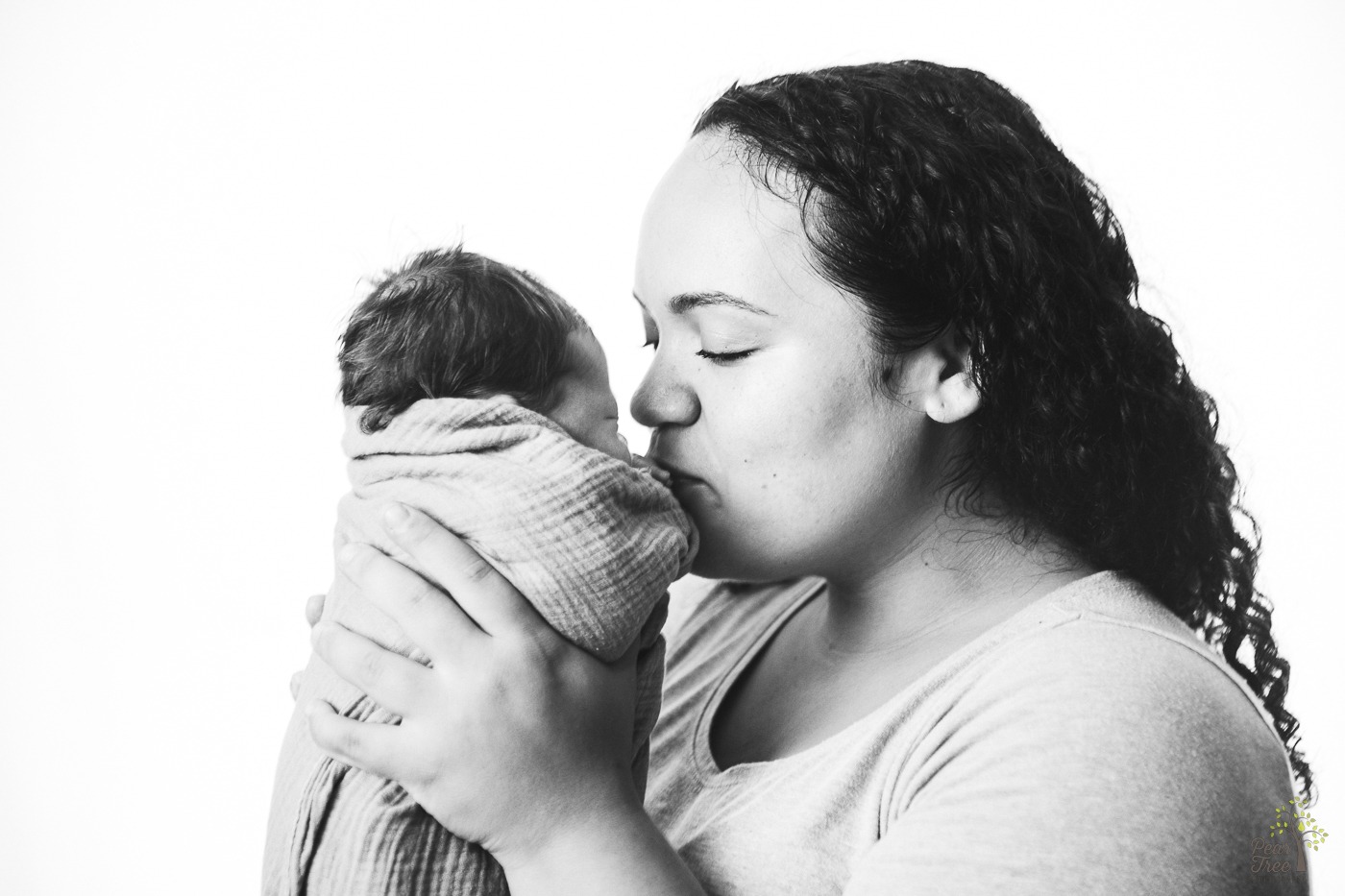 Black and white photograph of mom holding and kissing her newborn daughter