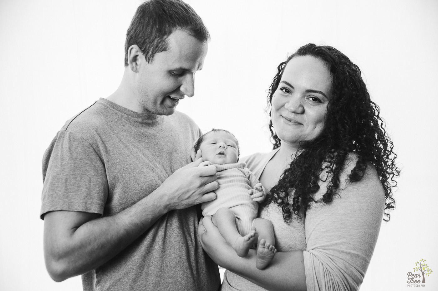 Black and white photograph of parents holding newborn daughter close and smiling