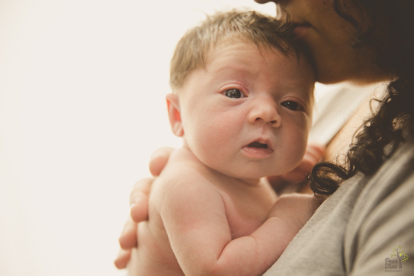 Mom holding newborn daughter close while she holds her head