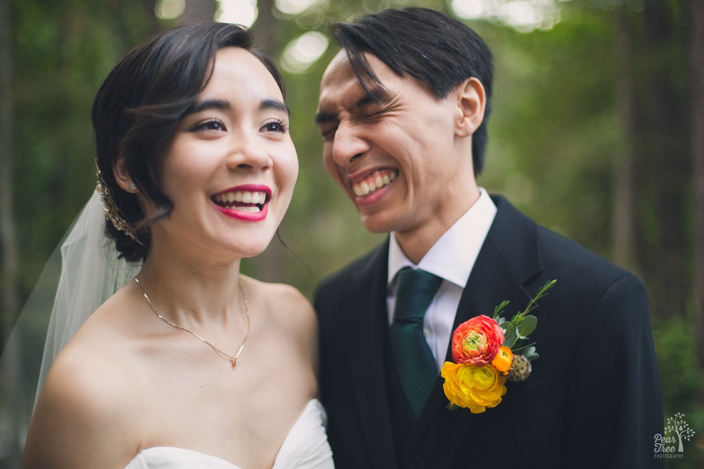 Laughing Asian wedding couple with the groom squeezing his eyes shut