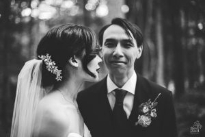Black and white photograph of Asian bride standing next to smiling Vietnamese husband