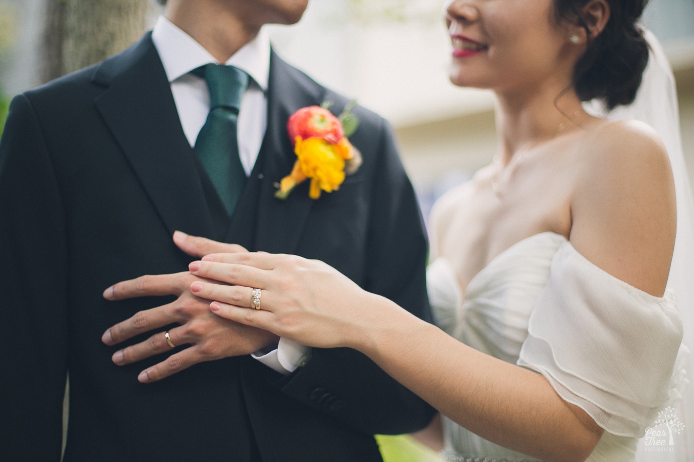 Ring shot of Asian wedding couple with bride's hand over the groom's hand on his chest