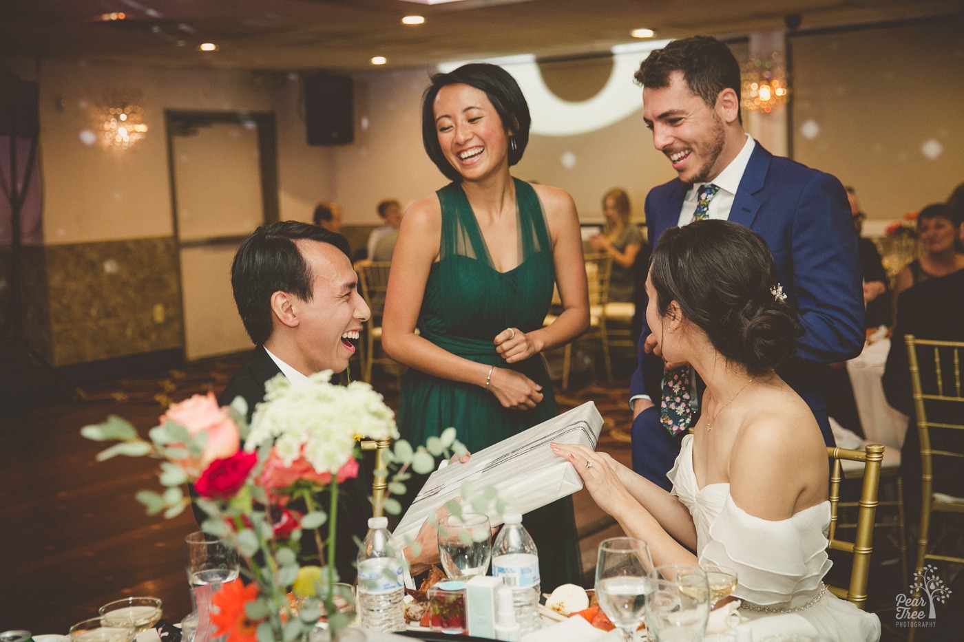 Asian wedding couple laughing and accepting presents from friends