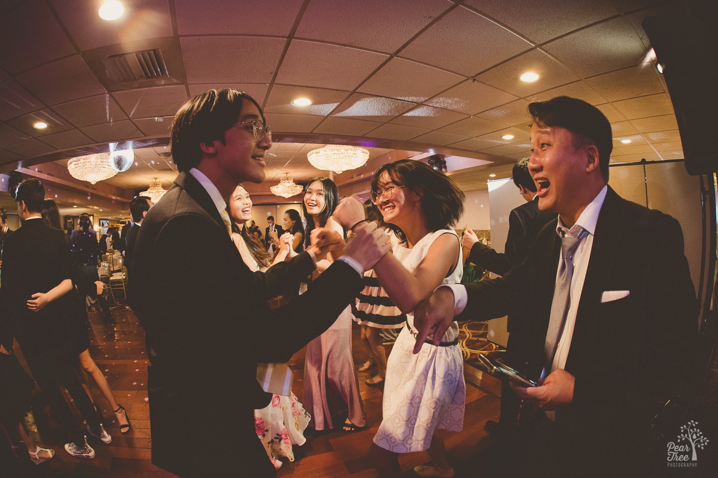 Asian dad dancing and having fun with his teenage children on the dance floor at a wedding reception