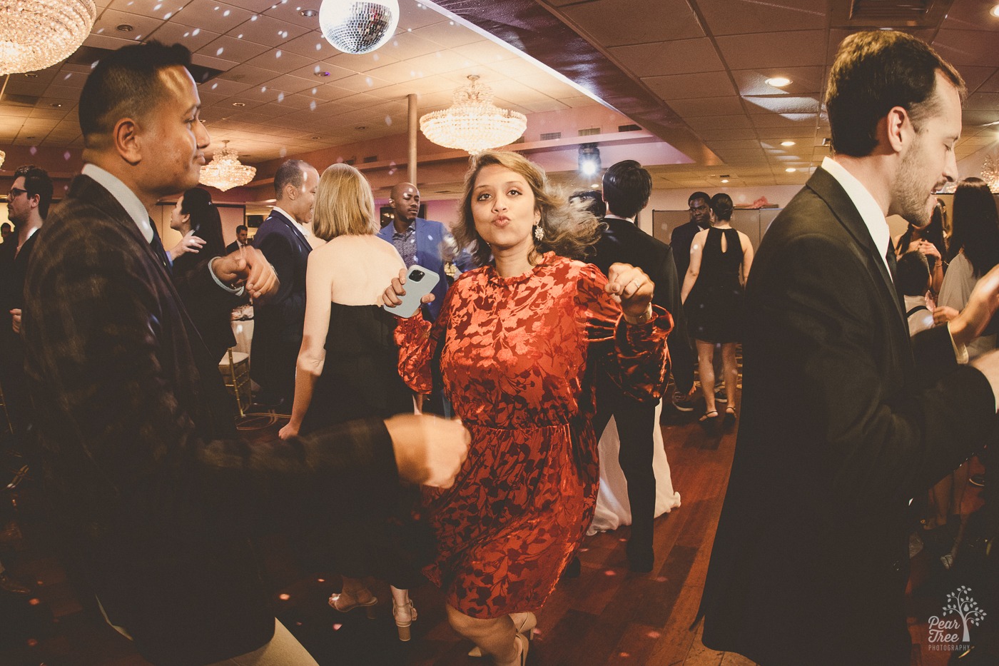 Woman in a red dress dancing and puckering her lips during a wedding reception at the Canton House