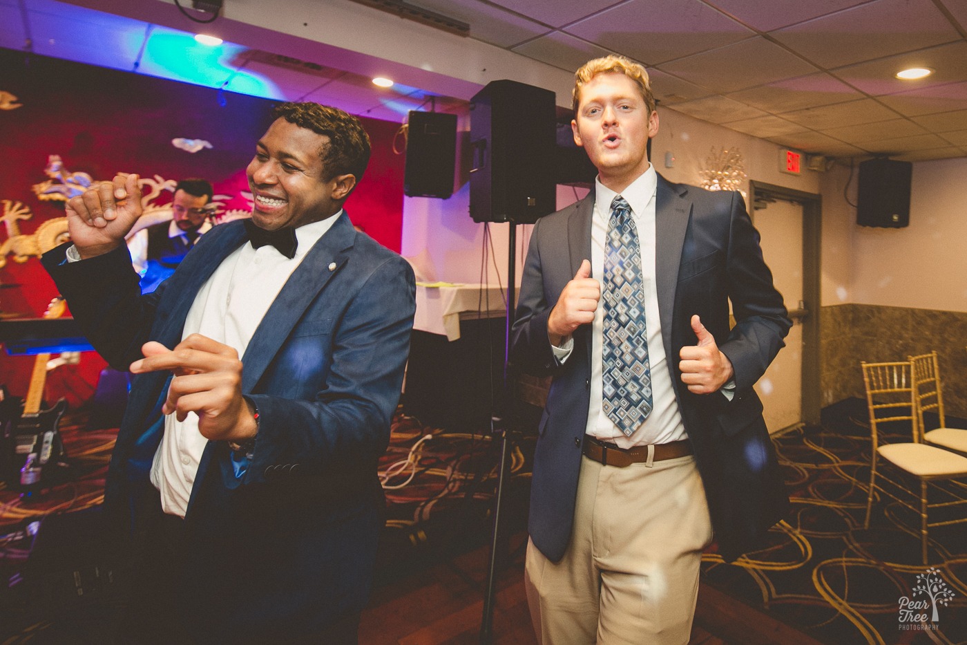 Two men in suits dancing and having fun at a wedding reception