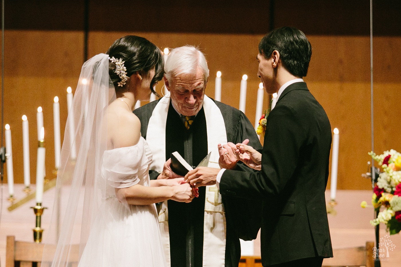 Officiant handing ring to Asian groom at Eastminster Presbyterian Church during wedding ceremony
