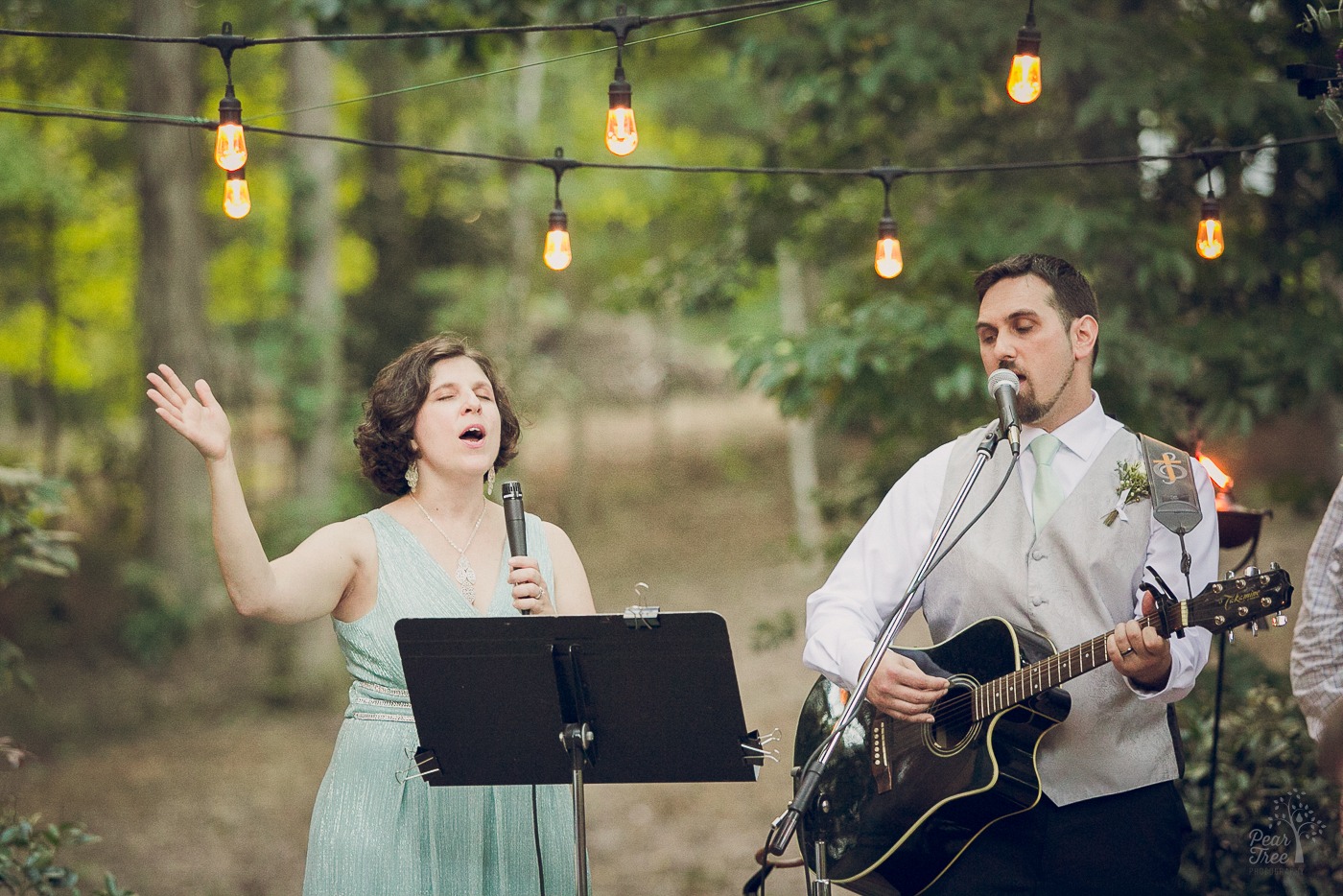 Husband and wife singing and playing the guitar in the middle of their wedding ceremony