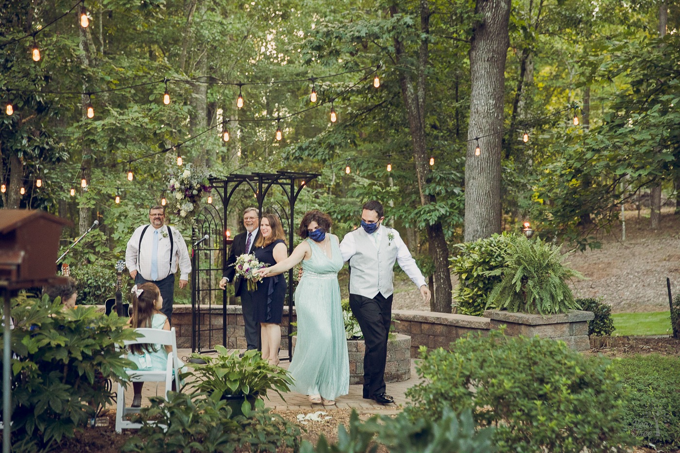 End of backyard wedding ceremony as bride and groom in masks make their exit