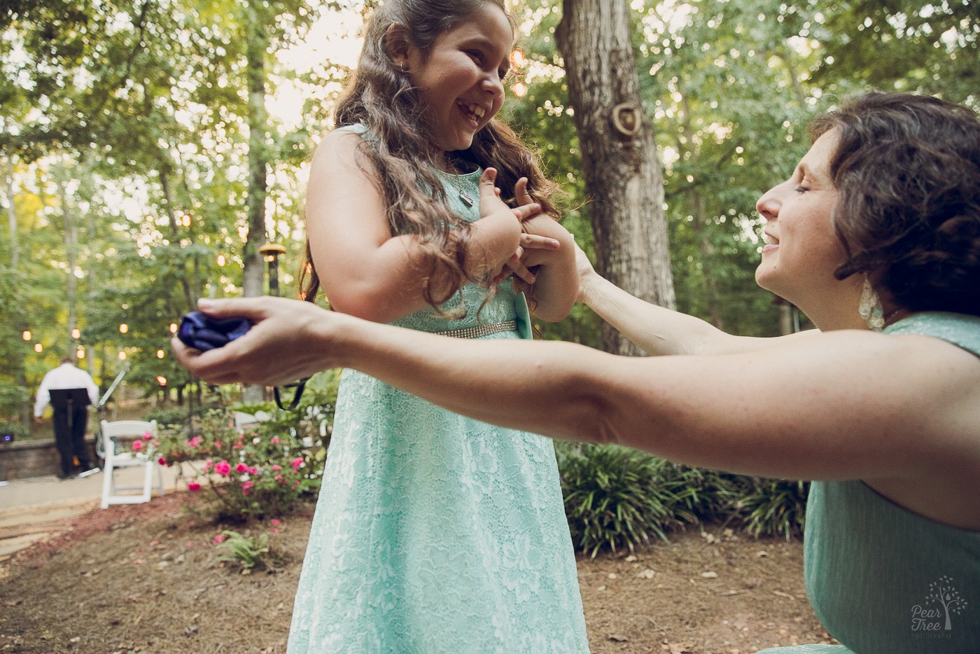 Mom squatting and outstretching her arms to her five year old smiling daughter