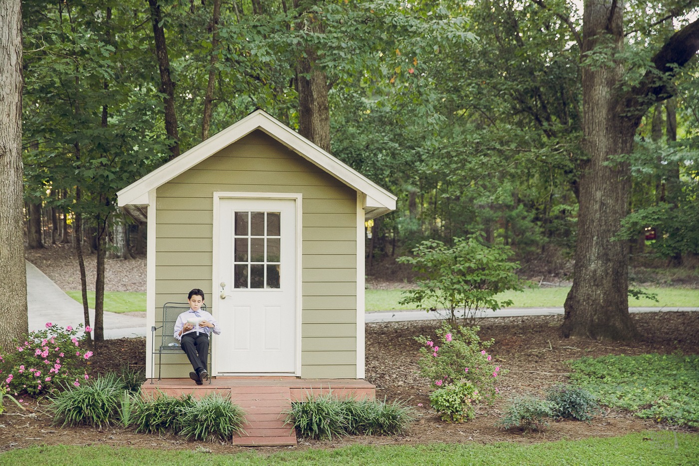 Bride's son sitting relaxed outside a pretty garden shed before the wedding