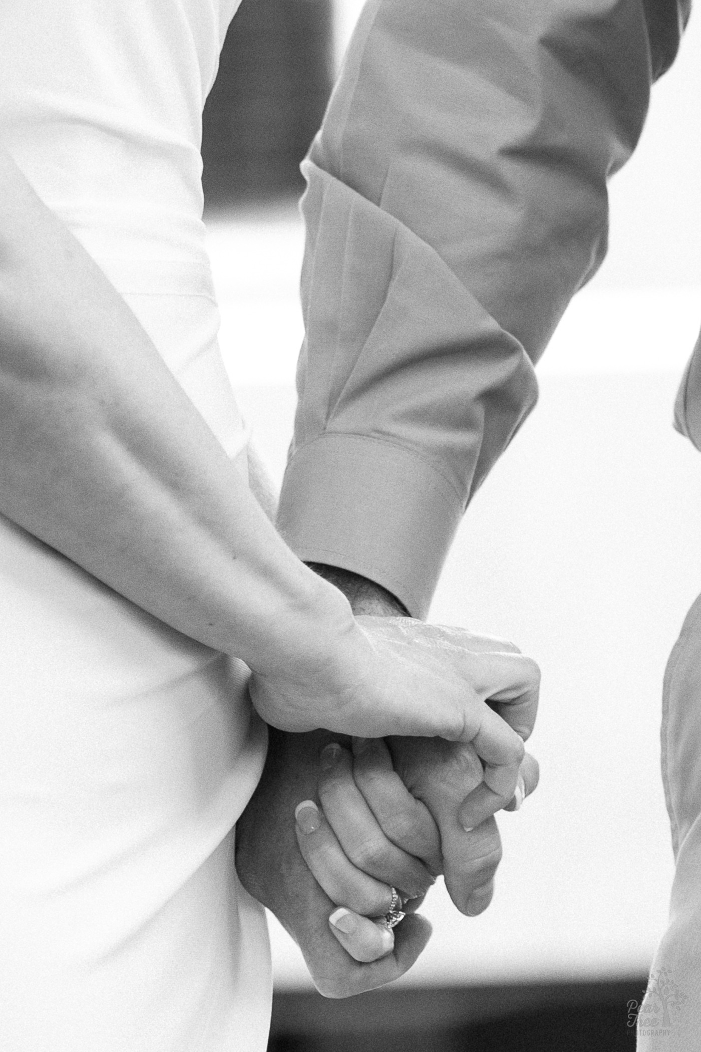 Black and white photograph of bride and groom hands holding each other