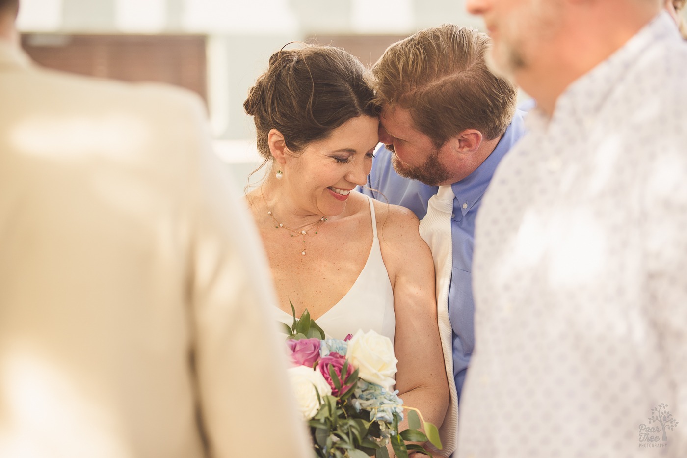 Bride smiling and resting her forehead on her groom's