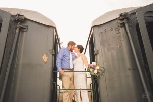 Bride and groom nuzzling noses while standing between two train cars at the Chattanooga Choo Choo Hotel
