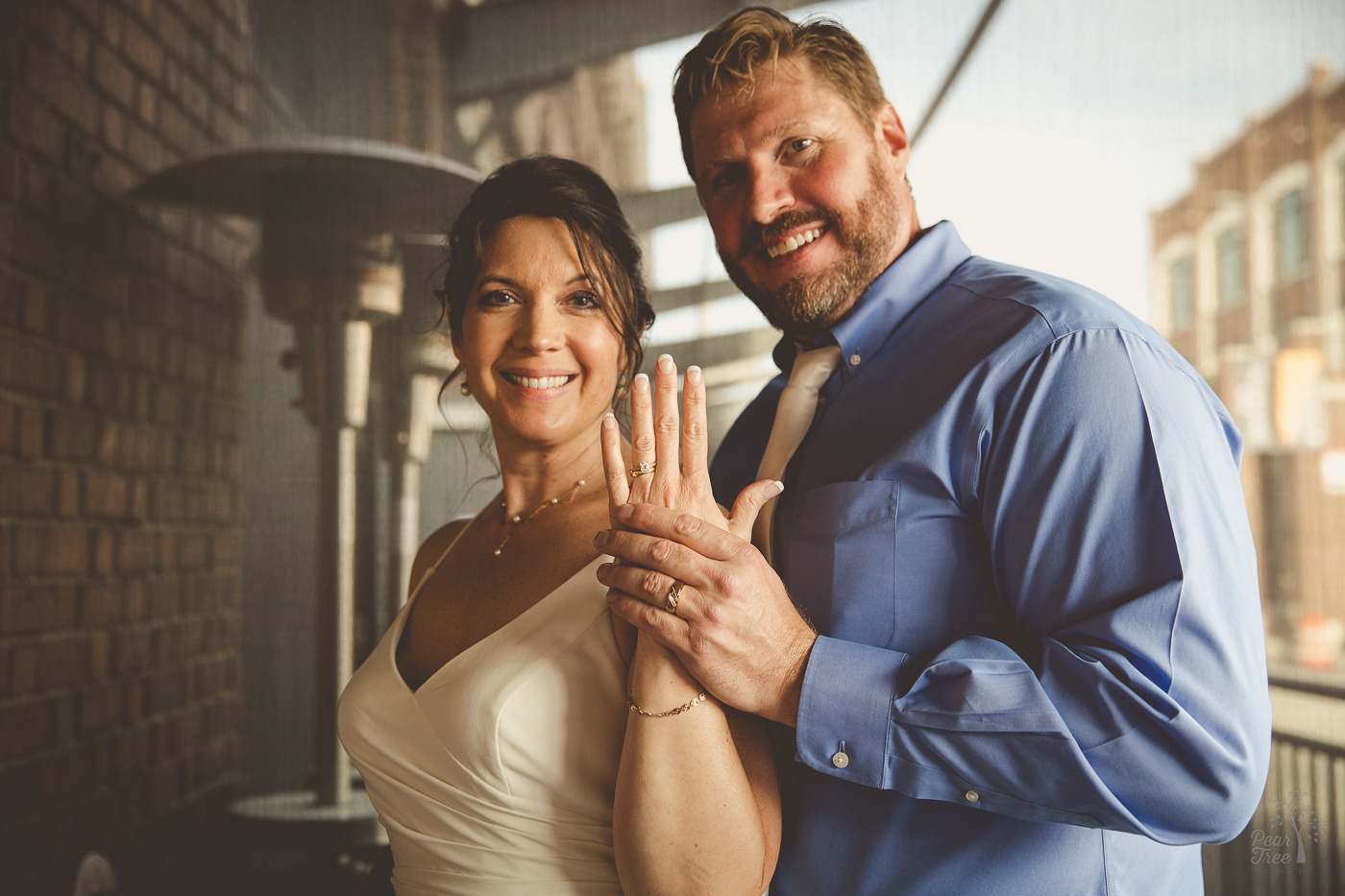 Ring shot of bride and groom holding hands up and smiling