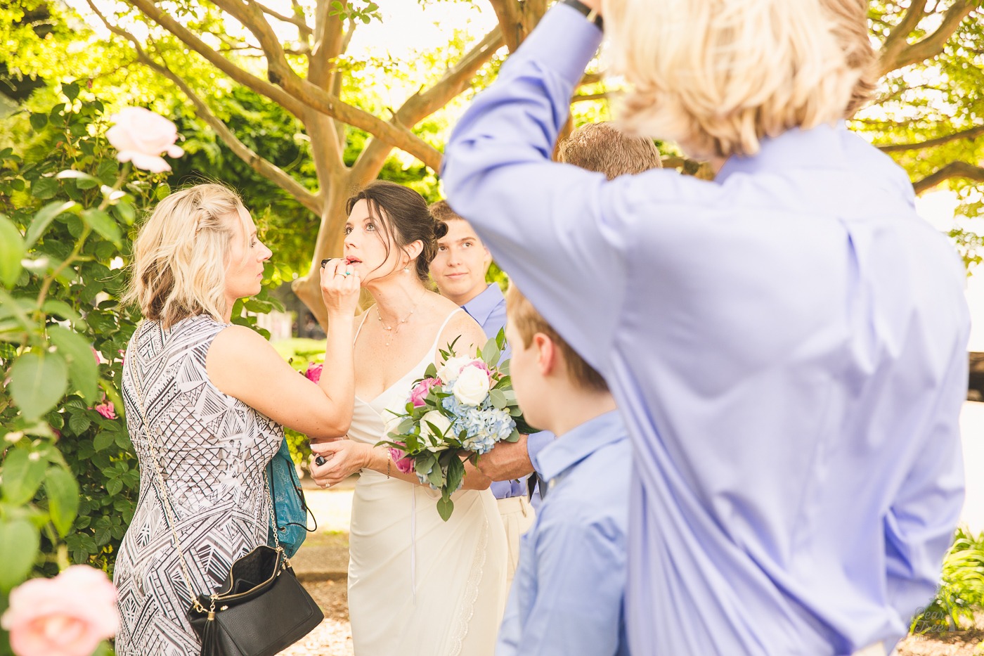 Friend applying lipstick to bride before wedding ceremony