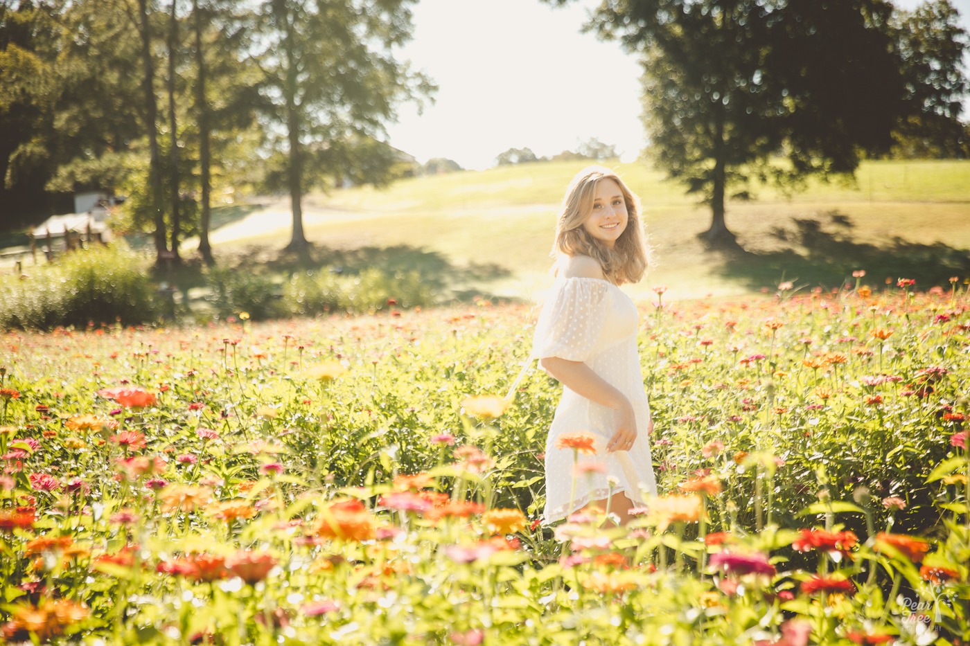 Creekview high school senior girl swishing her dress and smiling in a wildflower field