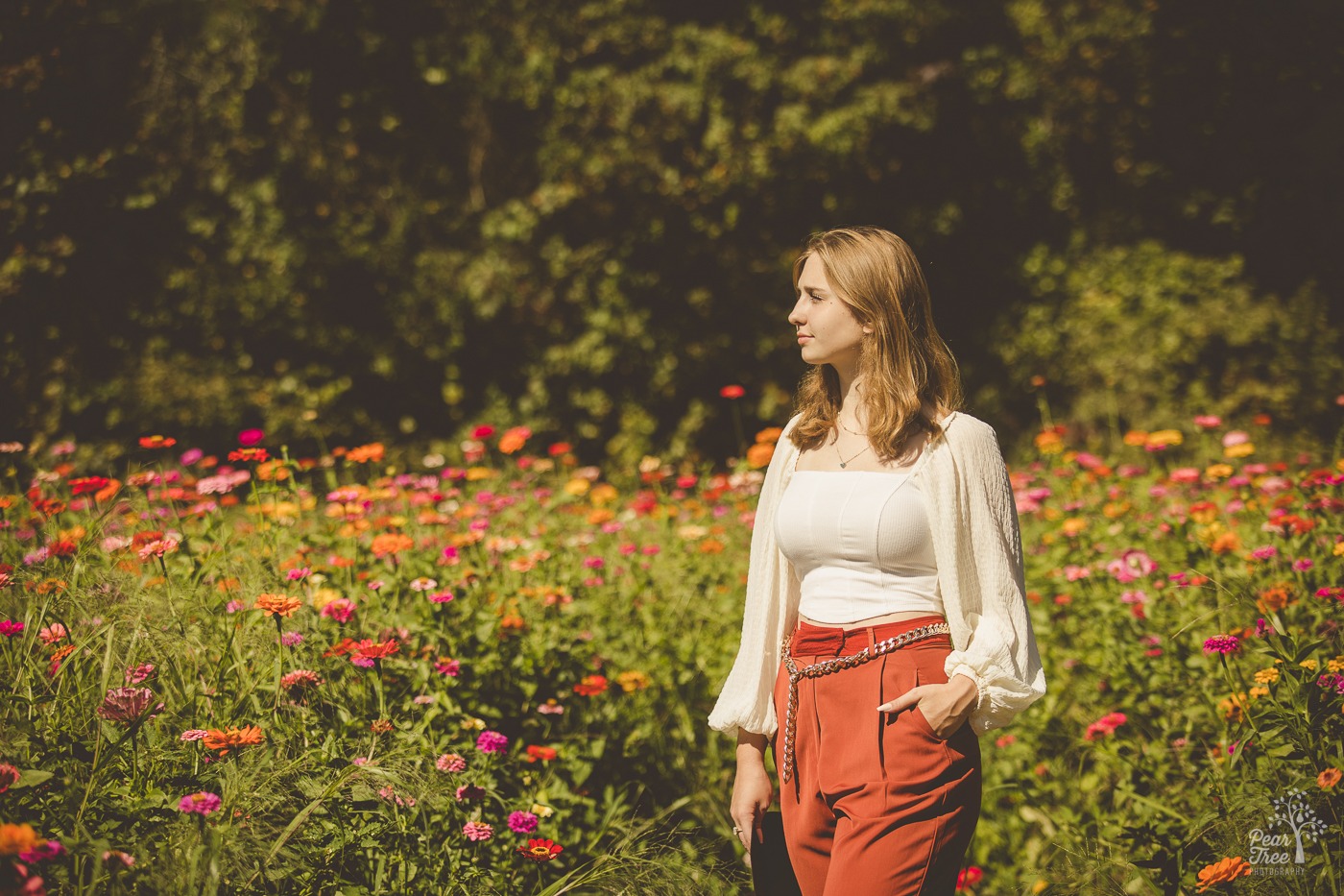 Beautiful Creekview high school senior girl standing with hand in pocket and looking out over a field of wildflowers