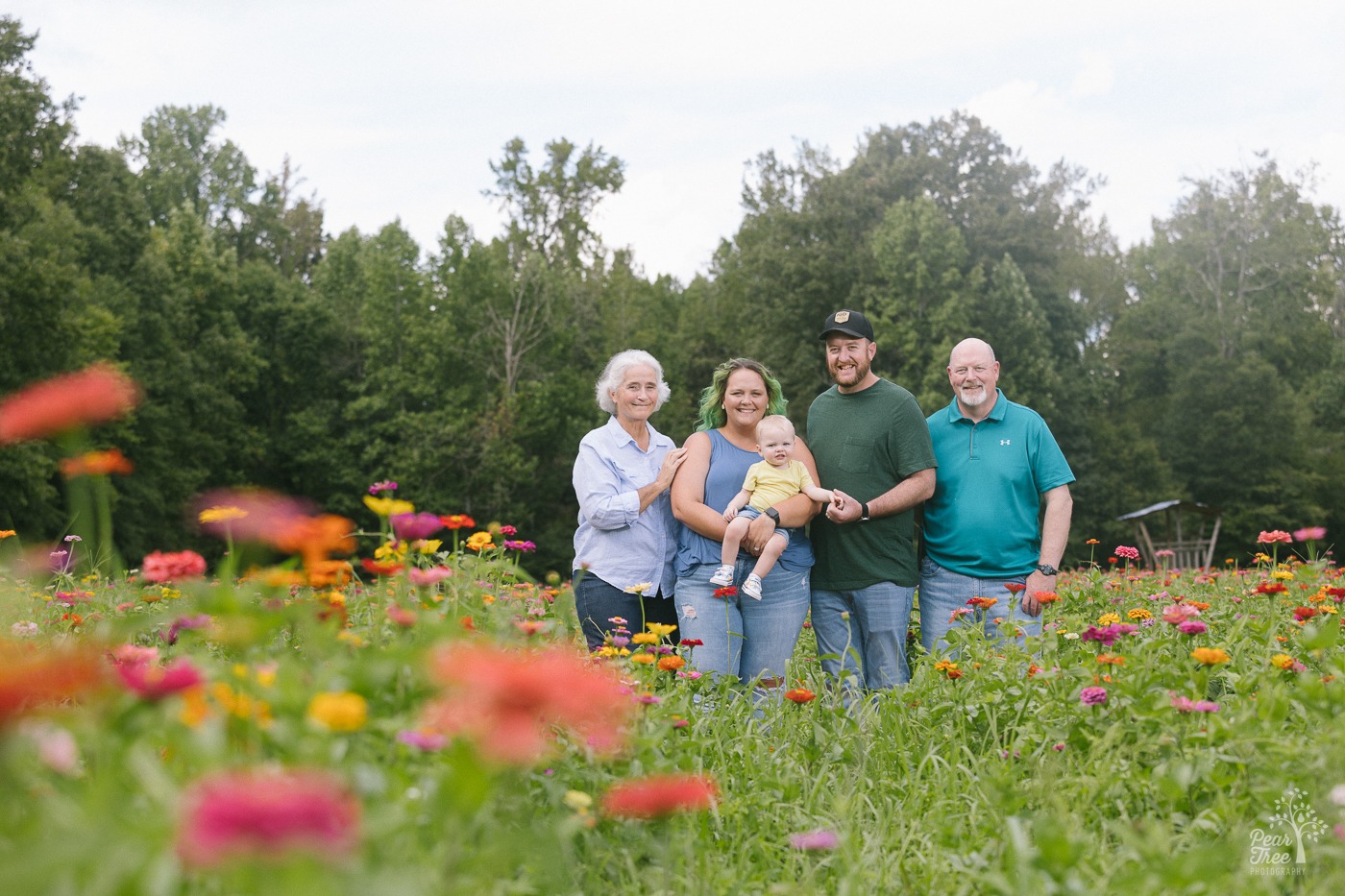 Multi-generational photo of one year hold, parents, and grandparents in a wildflower field