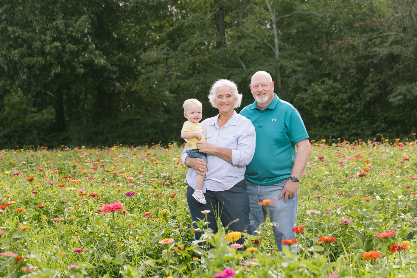 Grandparents holding their one year old grandson in a wildflower field