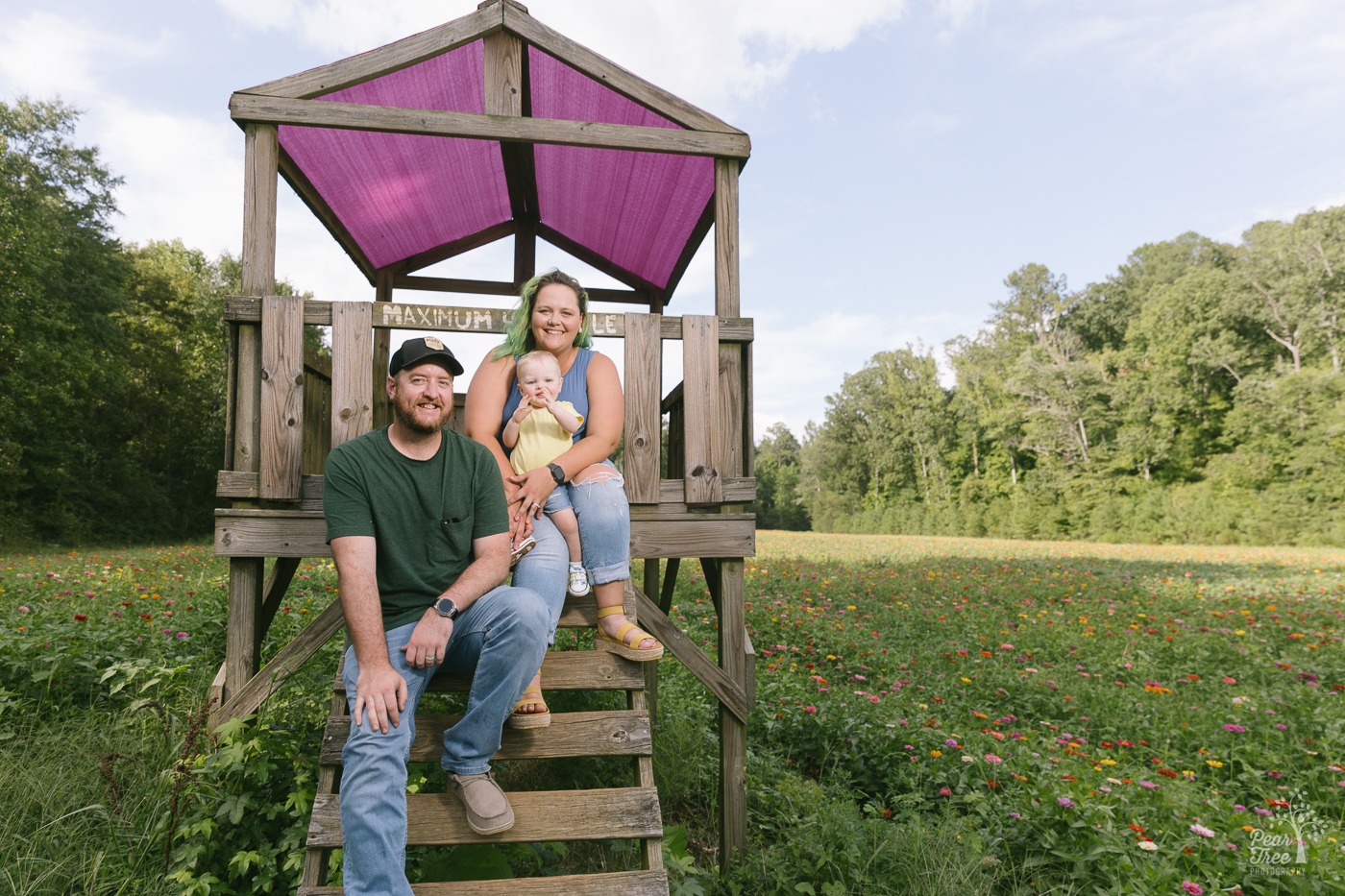 Happy parents and one year old son smiling in a flower field outside of Atlanta