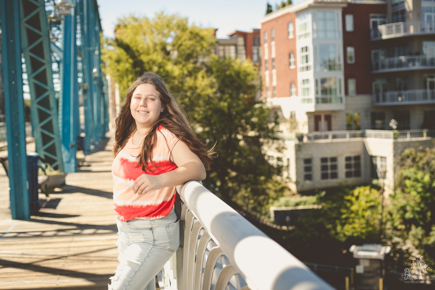 Pretty Woodstock high school senior girl leaning on Chattanooga bridge railing and smiling