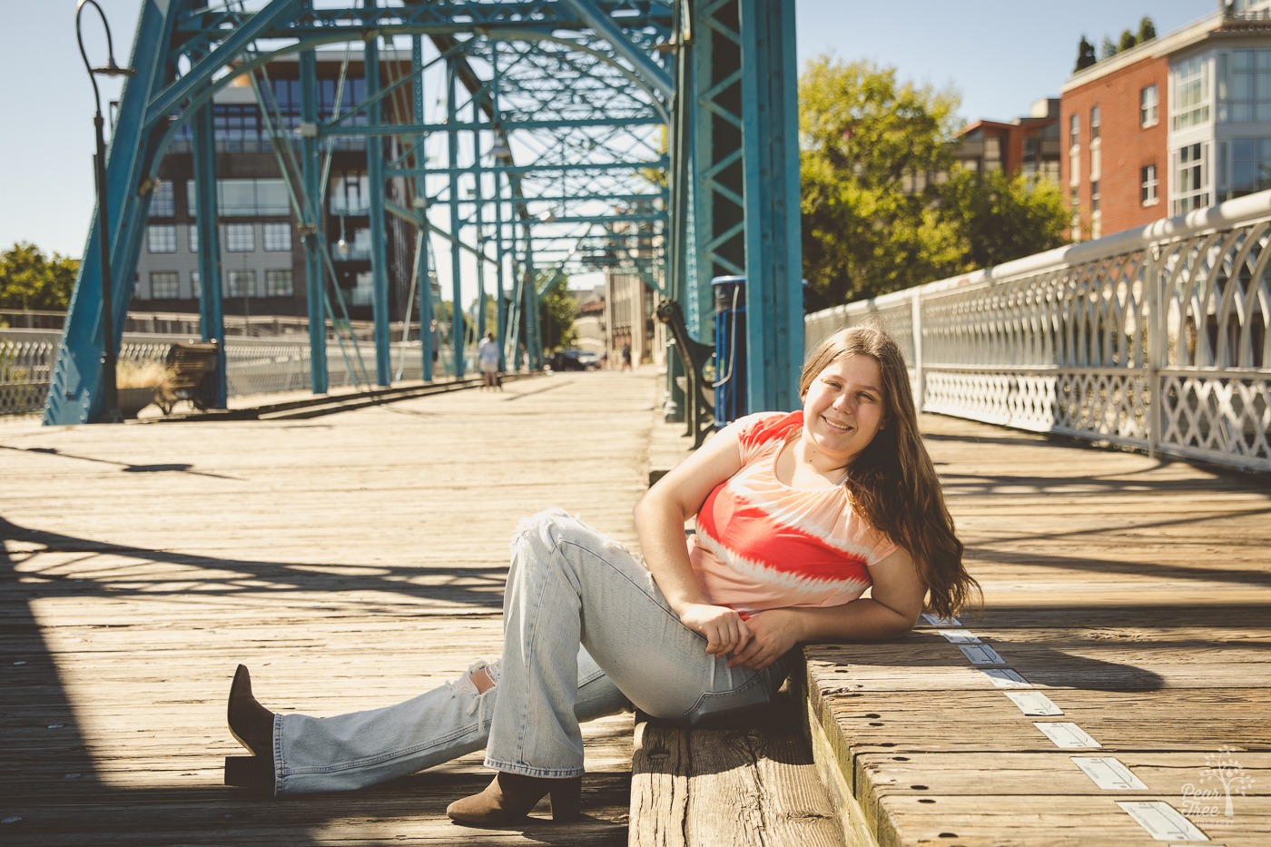 Pretty high school senior girl lounging on wooden step on Chattanooga blue bridge