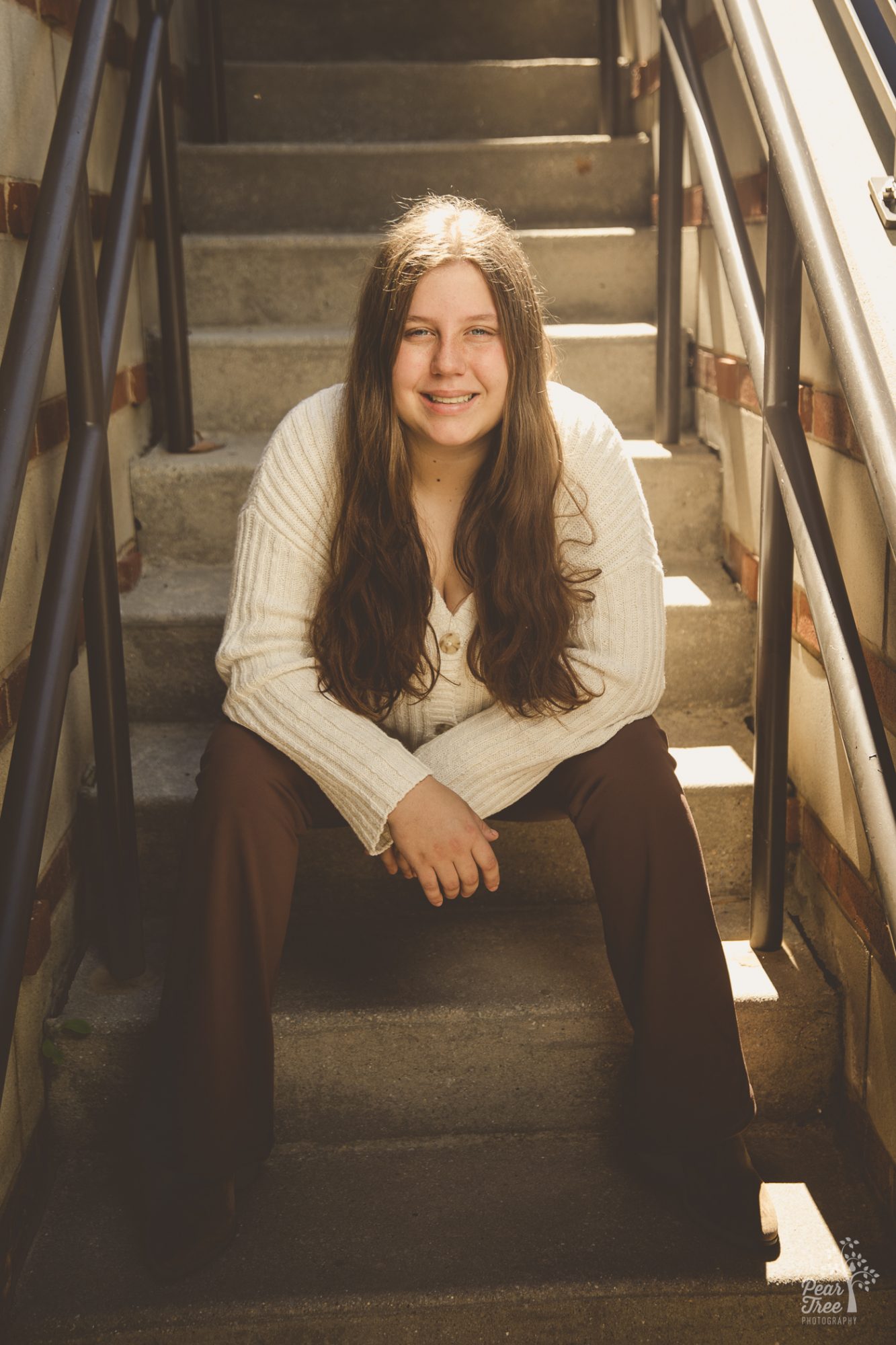 Woodstock high school senior girl sitting on steps in Chattanooga and smiling