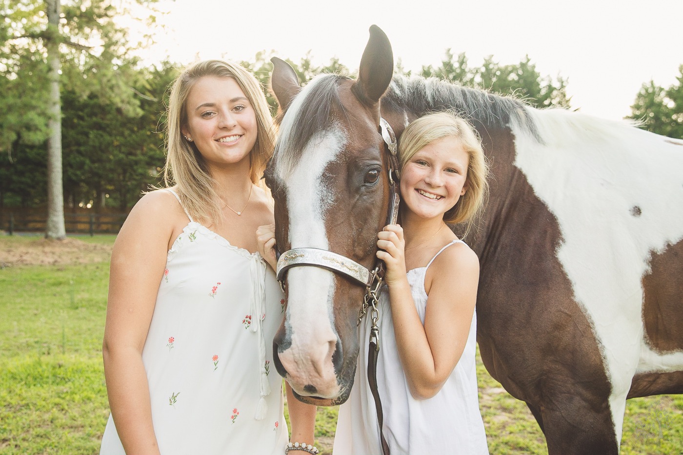 Two happy sisters with their paint horse standing in a Woodstock field