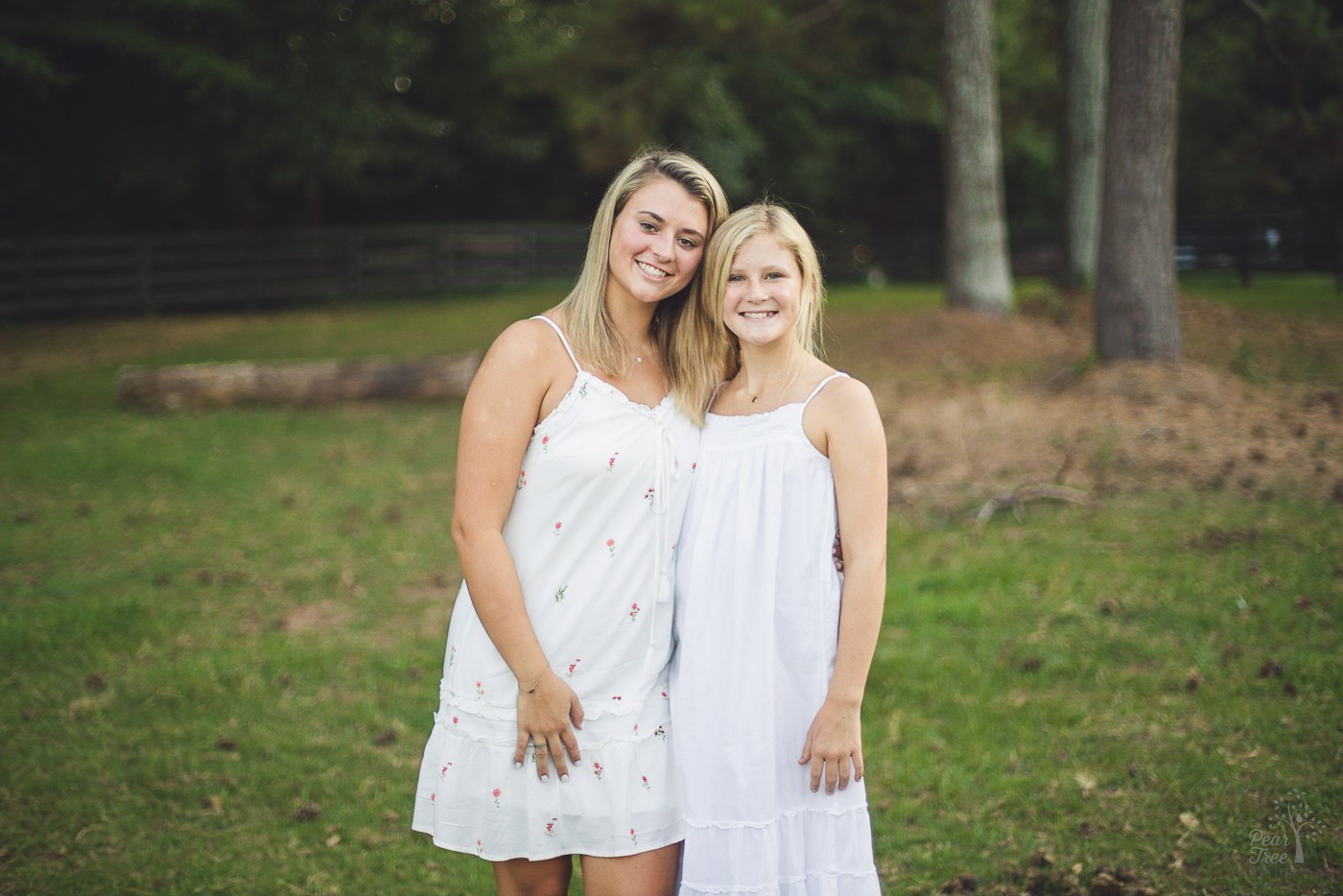 Two smiling teenage sisters in white sundresses