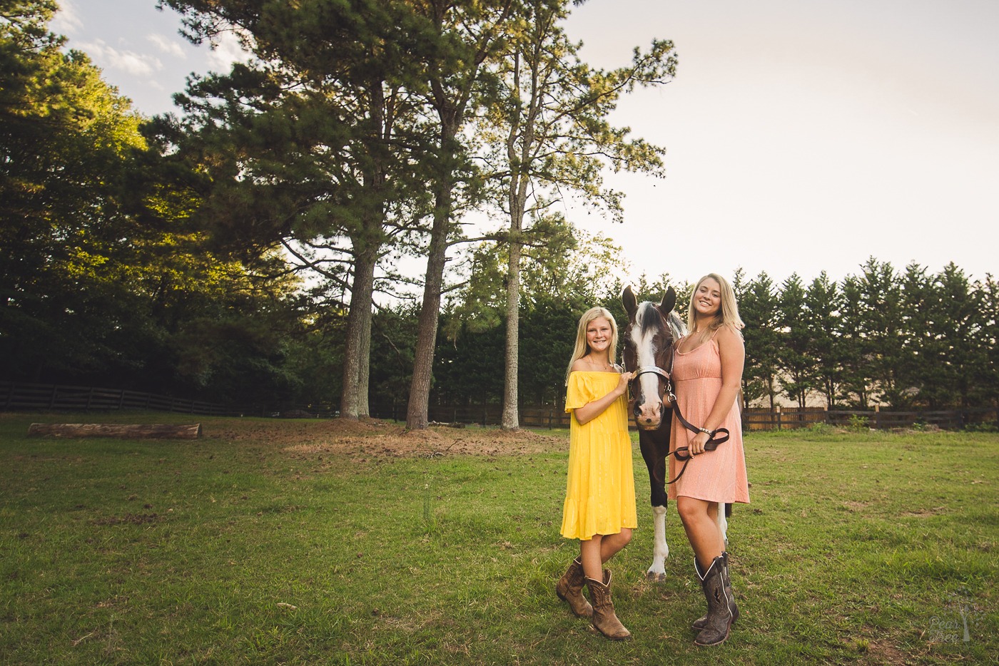 Two sisters smiling with their paint horse in a summer field in Woodstock, GA