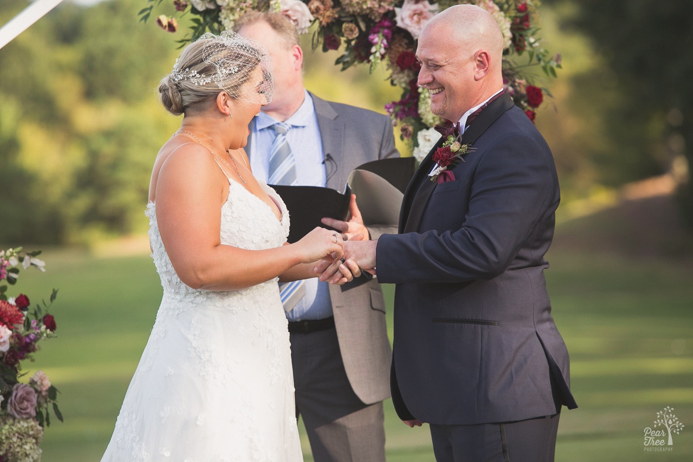 Bride laughing big as she puts ring on her fiance's finger at Cumming Polo Fields