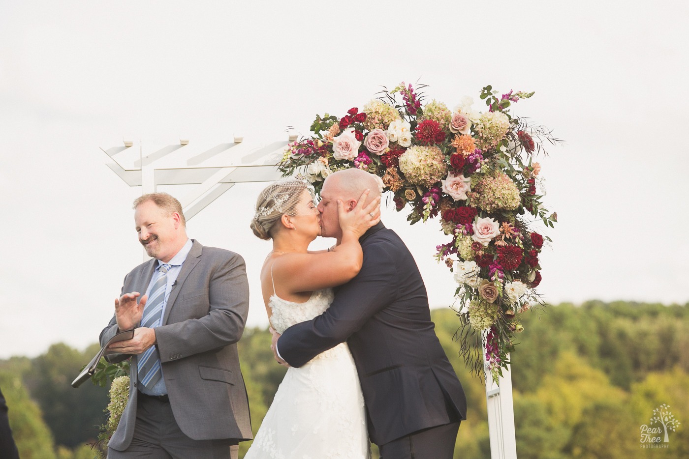 Bride grabbing groom's head and kissing him while he pulls her close around the back of her waist after Cumming Polo Fields wedding ceremony