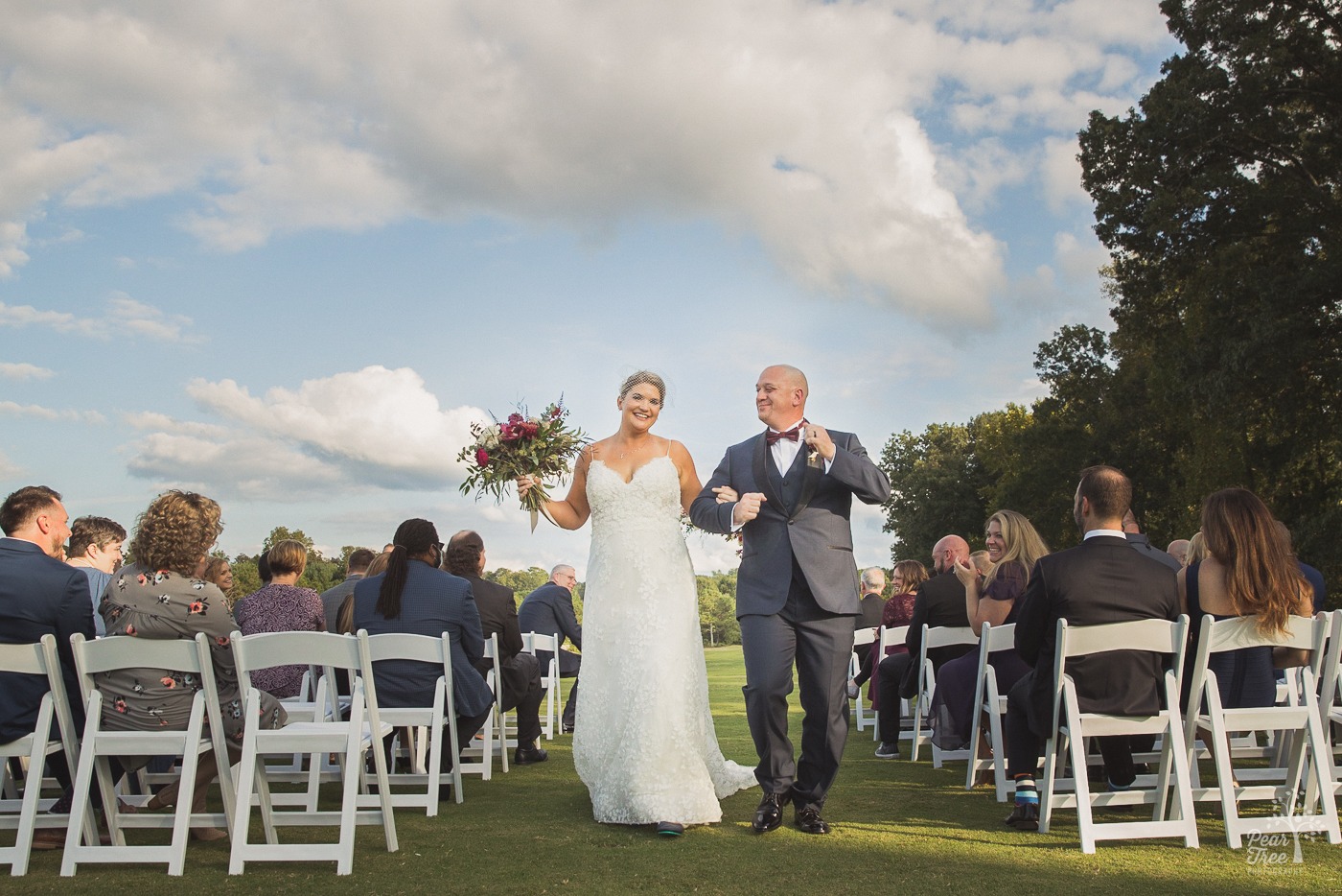 Bride and groom dancing down the aisle after their wedding ceremony at Cumming Polo Fields