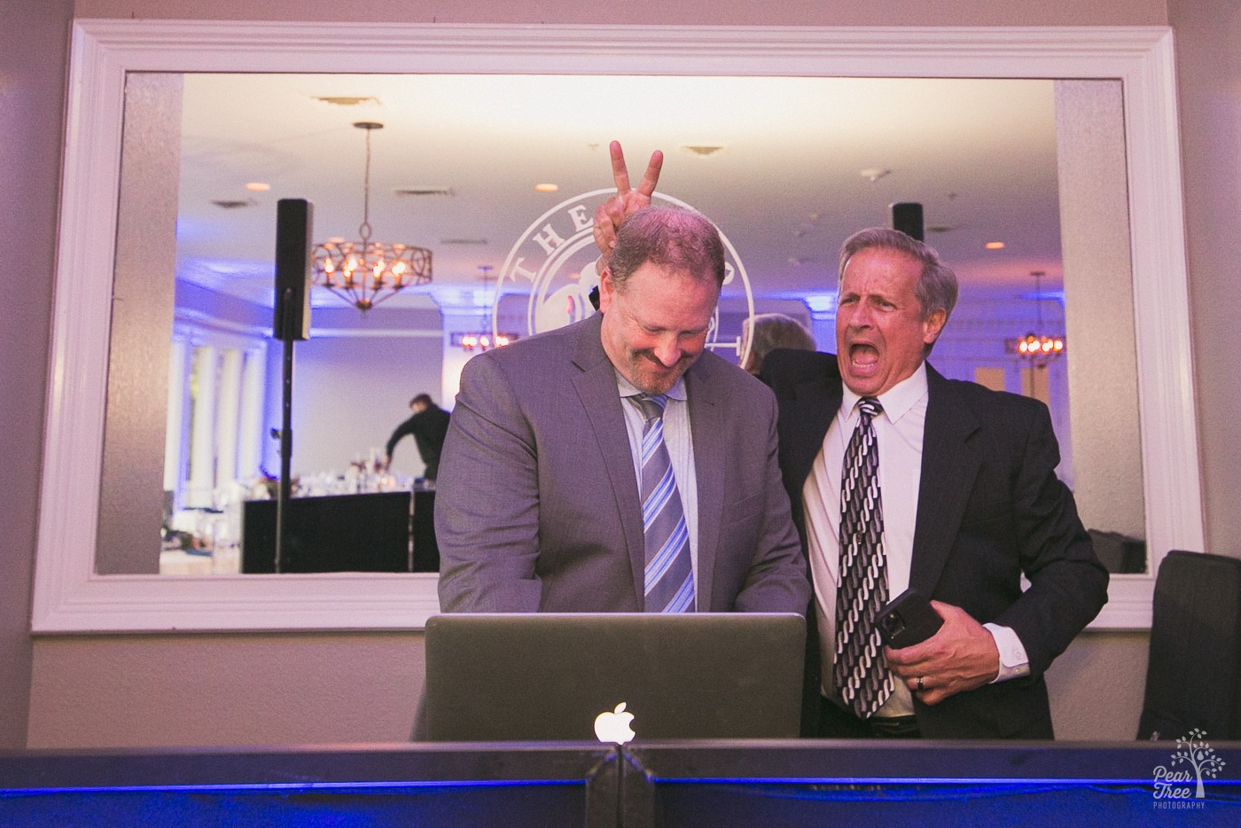 Wedding guest making bunny ears behind DJ's head