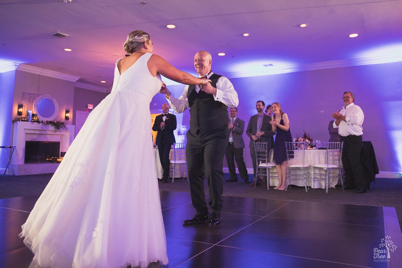 Bride and groom dancing while friends clap and cheer